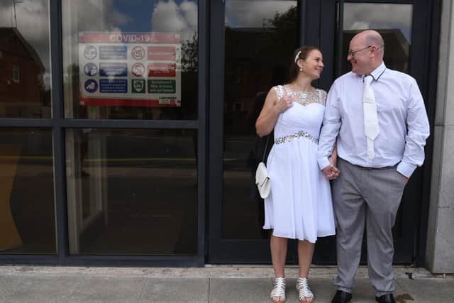 A sign of the times - the wedding couple pictured by the Covid-19 advisory notice posted at the entrance to the registry office.