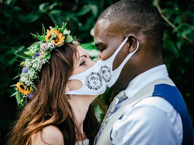 A wedding kiss with a difference -  Hollie and Malcolm model the bespoke face masks guests wore at their wedding Photo: Tiffany LS Photography