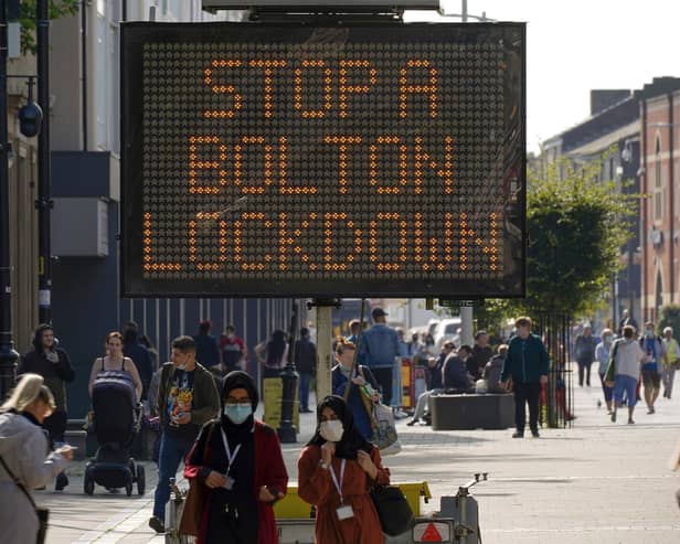 People walk past an electronic sign displaying health advice about COVID-19 in Bolton (Photo by Christopher Furlong/Getty Images)