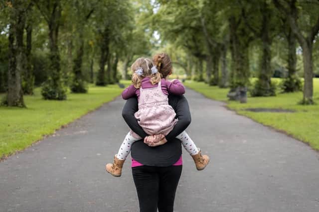 Laura carries her eldest daughter, years after being told she would never be a mother. Credit: Frazer Faulkner Photography