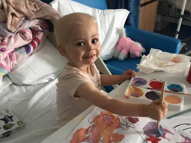 Two-year-old Amalie sits cheery and smiling despite her diagnosis