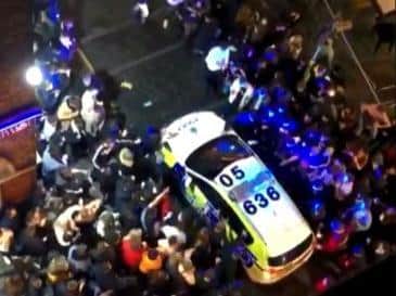 This picture shows a police car surrounded in the city's Concert Square after revellers spilled out of pubs after the 10pm curfew last night (Tuesday, October 13)