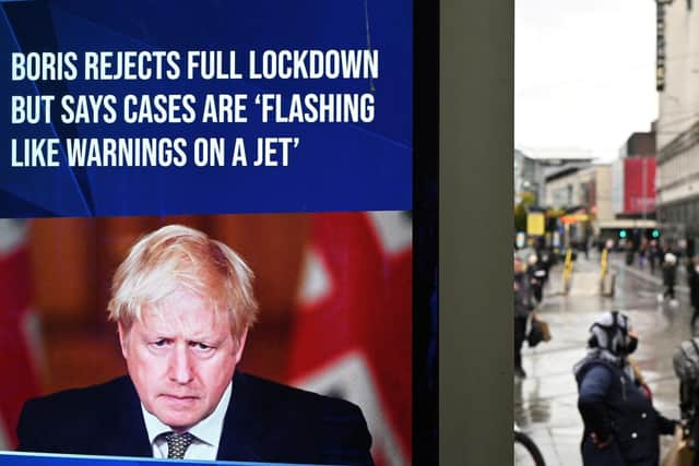 A news display features Britain's Prime Minister Boris Johnson as shoppers make their way along the streets of Manchester