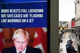 A news display features Britain's Prime Minister Boris Johnson as shoppers make their way along the streets of Manchester