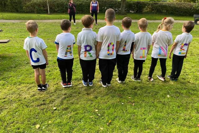 Classmates of Olivia Dempsey, at Hambleton Primary, spell at the name of her mum Caroline with their special T-shirts when they ran the marathon for her
