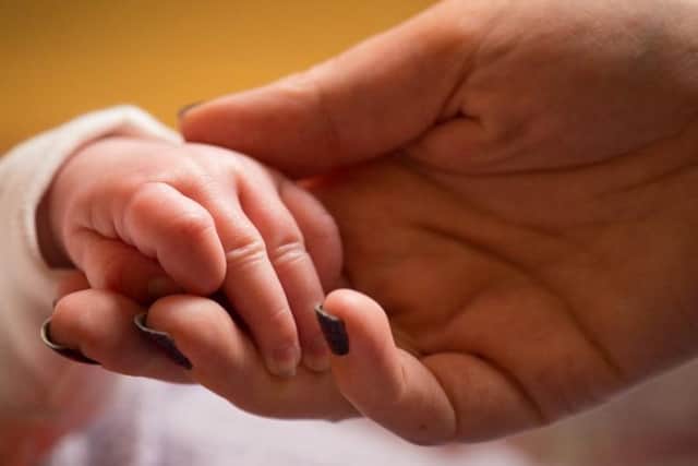 An undated file photo of a mother holding the hand of a new baby (Picture: PA Wire/PA Images)