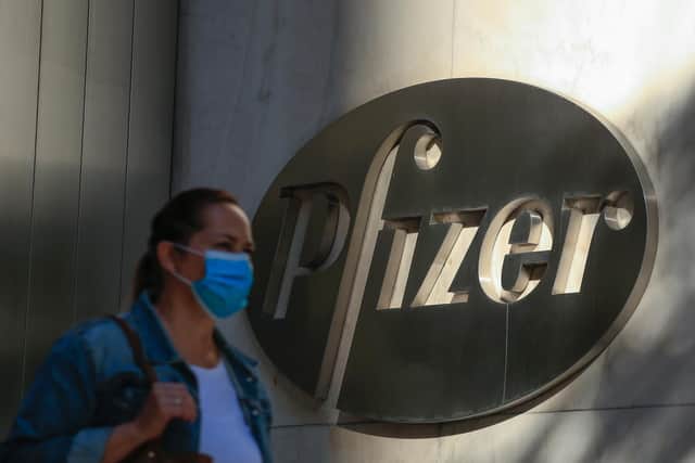 A woman wears a facemask as she walks by the Pfizer world headquarters in New York