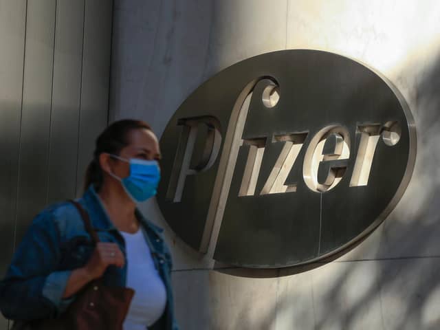 A woman wears a facemask as she walks by the Pfizer world headquarters in New York