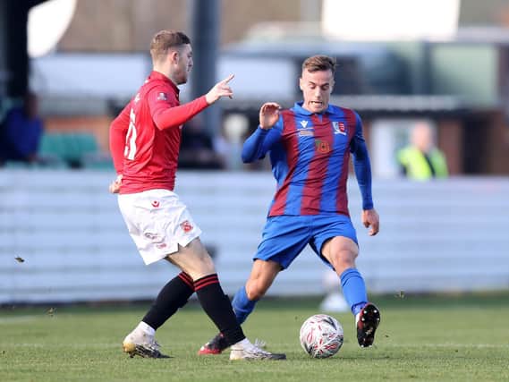 Samuel Coombes of Maldon & Tiptree FC is challenged by Morecambe's Ryan Cooney
