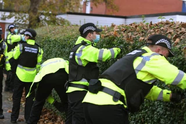 Officers search hedges for weapons as part of Operation Sceptre.