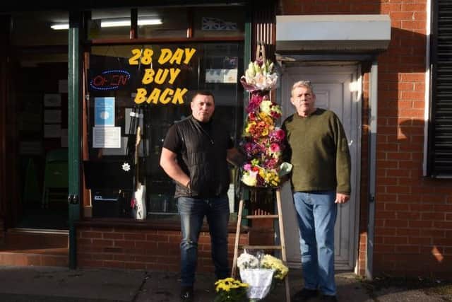 Lee and Neil Cheetham with the floral tribute to former window cleaner Arthur