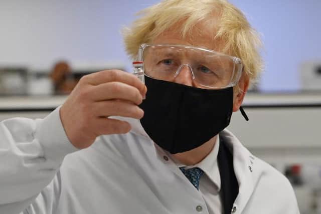 Britain's Prime Minister Boris Johnson poses for a photograph with a vial of the AstraZeneca/Oxford University COVID-19 candidate vaccine, known as AZD1222, at Wockhardt's pharmaceutical manufacturing facility in Wrexham, north Wales, on November 30, 2020.
