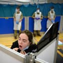 A woman undertakes a swab test at a temporary COVID-19 testing site at a leisure centre