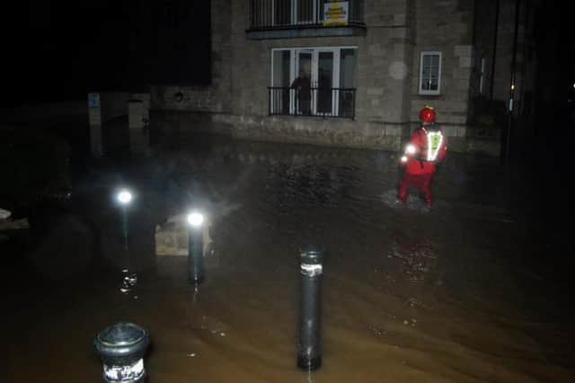 A rescue worker wades through floodwater.