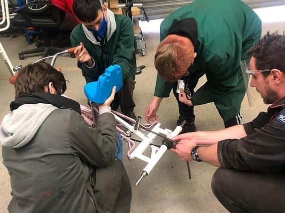 Andy and Myerscough College students working on the bike, making it suitable for Tia's condition