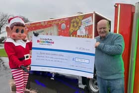 Kath Kay dressed as the 'Elf Behavin' Badly' with Doug Smith and 'Harry the Christmas Lorry', with a £13,187.01 cheque for Brian House Children's Hospice