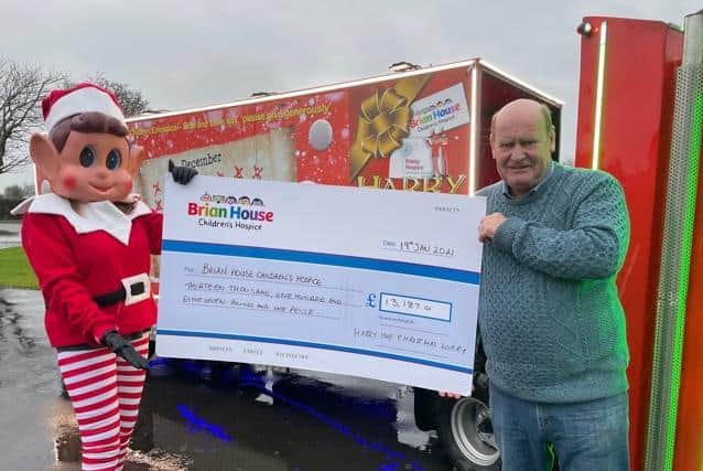 Kath Kay dressed as the 'Elf Behavin' Badly' with Doug Smith and 'Harry the Christmas Lorry', with a £13,187.01 cheque for Brian House Children's Hospice