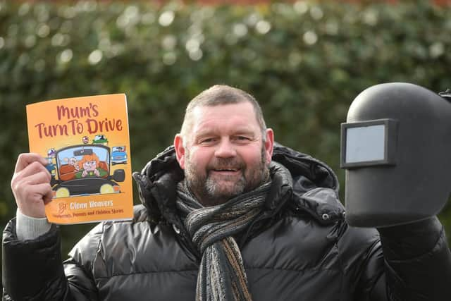 Two jobs for Glenn - pictured holding one of his books and his welding safety helmet