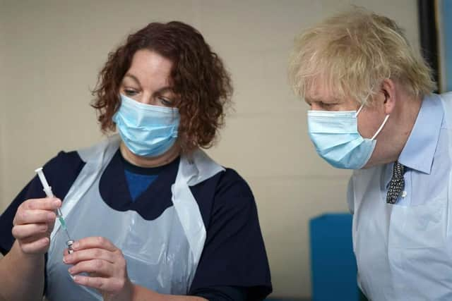 Prime Minister Boris Johnson is shown how to prepare the vaccine by advance nurse practitioner Sarah Sowden as he visits a COVID-19 vaccination centre