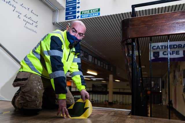 Site supervisor Wes Kendall sticks down one way stickers to maintain social distancing at Archbishop Temple CofE School. Photo: Kelvin Stuttard.