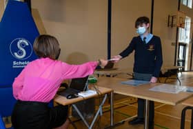 School Business Support Officer Julie Brennan hands year 8 pupil Harrison his card which he will give to a coronavirus tester. Photo: Kelvin Stuttard.