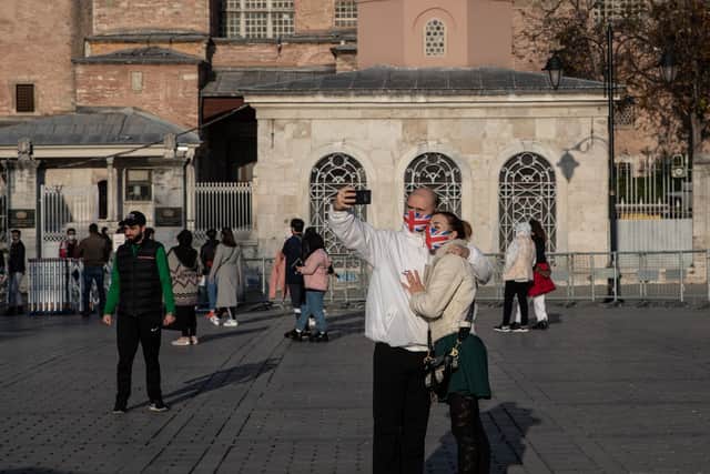 Tourists take a selfie in front of the Hagia Sophia Grand Mosque during a national weekend coronavirus lockdown on December 06, 2020, in Istanbul, Turkey