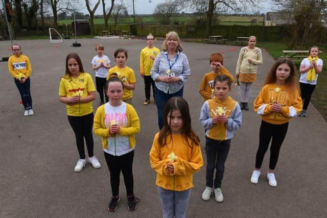 Pupils and staff at Great Eccleston Cop School were a sea of yellow yesterday as they stood to remember those who had lost their lives to the virus last year.