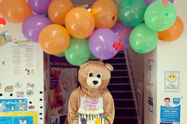 A bear delivers a cake to Busy Bears Nursery