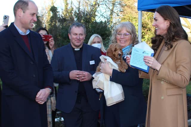 The Duke and Duchess are all smiles as Denise Gee, Charity Manager at ELHT, introduces them to trainee therapy puppy dog ‘Alfie’ while the Trust’s Chaplain, Rev. Canon Andrew Horsfall, looks on. Photo credit: ELHT