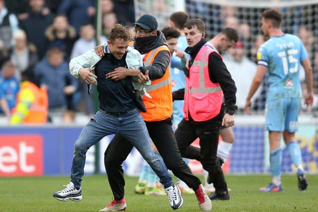 A pitch invader is apprehended by stewards