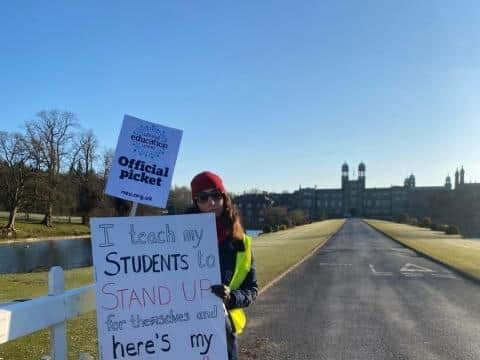 A protester holds up signs outside Stonyhurst as teachers strike over pensions.