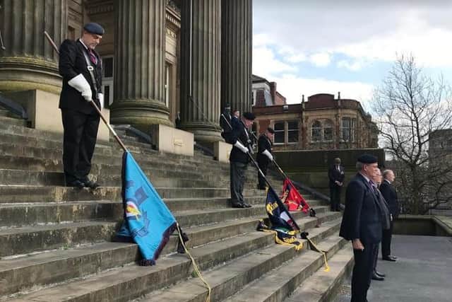 Standards from all three branches of the Armed Force are lowered for the national two-minute silence on the steps of the Harris.