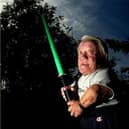 R2D2 actor Kenny Baker poses at his home in Preston with a light sabre for the 30th anniversary of the release of Star Wars: A New Hope