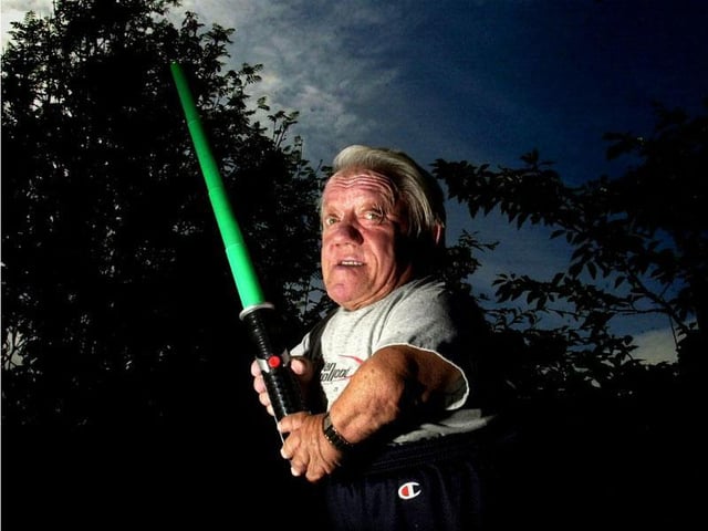 R2D2 actor Kenny Baker poses at his home in Preston with a light sabre for the 30th anniversary of the release of Star Wars: A New Hope