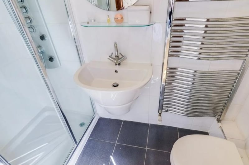 Three piece suite comprising low flush w.c., wall mounted wash basin with chrome mixer tap, shower enclosure with body jet shower and hose attachment, tiled walls and floor, extractor vent and a chrome ladder style towel radiator.