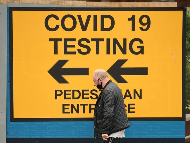 A pedestrian walks past a sign directing members of the public to a Covid-19 testing centre in Bolton,