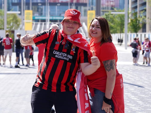 Two Morecambe fans pose outside the ground.