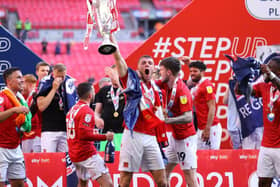 Morecambe skipper Sam Lavelle lifts the League Two play-off final winners' trophy
