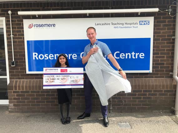Baker Saara with Rosemere Cancer Foundation’s chief officer Dan Hill and one of the 500 radiotherapy wraps/gowns her donation has bought