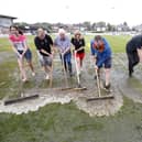 Standing water is swept off the pitch at Bamber Bridge's Sir Tom Finney Stadium