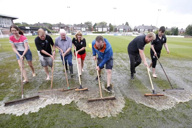 Standing water is swept off the pitch at Bamber Bridge's Sir Tom Finney Stadium