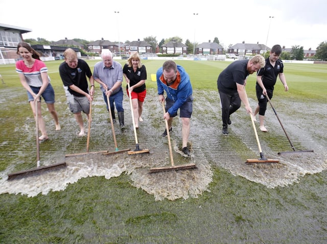 Standing water is swept off the pitch at Bamber Bridge's Sir Tom Finney Stadium