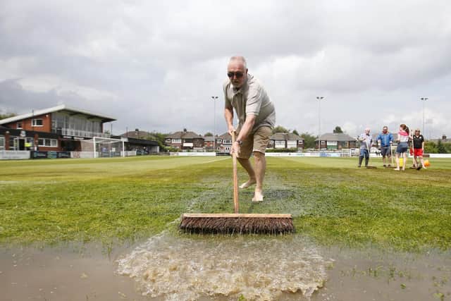 Attempts are made to clear the pitch of water
