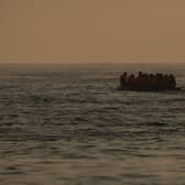 An inflatable craft carrying migrant men, women and children crosses the shipping lane in the English Channel.