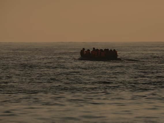 An inflatable craft carrying migrant men, women and children crosses the shipping lane in the English Channel.