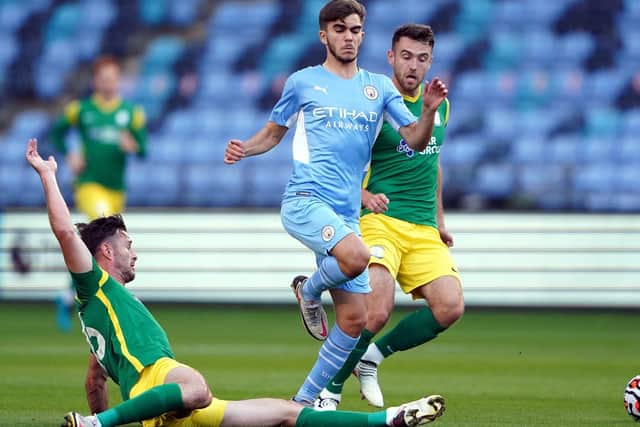 PNE defender Andrew Hughes slides in to tackle Manchester City's Iker Pozo as Ben Whiteman closes in