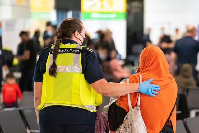 A member of Border Force staff assists an Afghan refugee on her arrival on an evacuation flight from Afghanistan, at Heathrow Airport