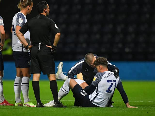 Preston North End striker Connor Wickham is treated on the pitch by physio Matt Jackson after injuring his hamstring against Cheltenham at Deepdale