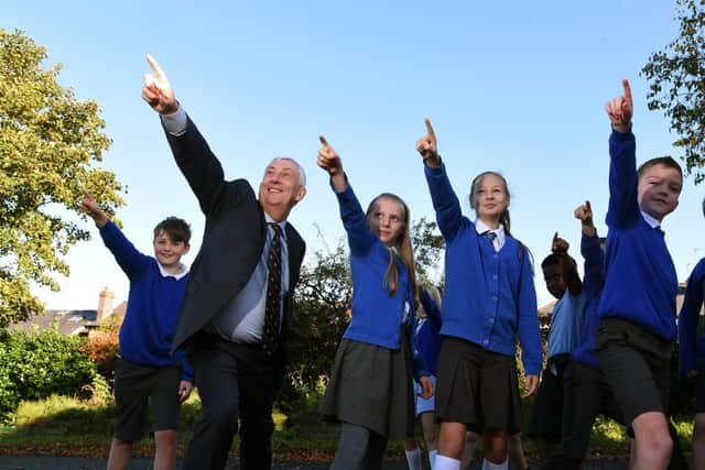 Sir Lindsay and the children are pointing towards the school's 59 solar panels.