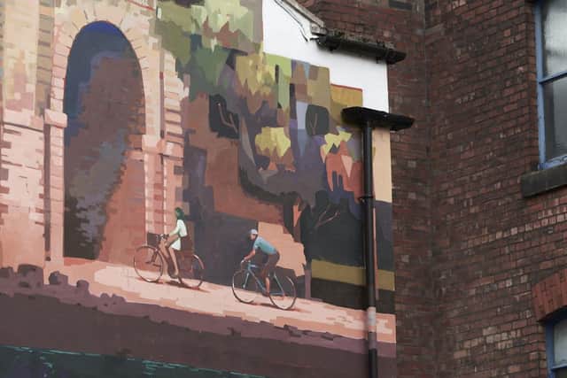 The mural features a cyclist riding through Avenham and Miller Parks with the East Lancashire railway bridge and historic Park Hotel in the background.